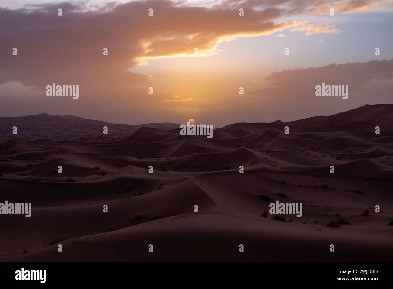 Un vasto paesaggio desertico adornato da dune di sabbia e un affascinante tramonto Foto Stock