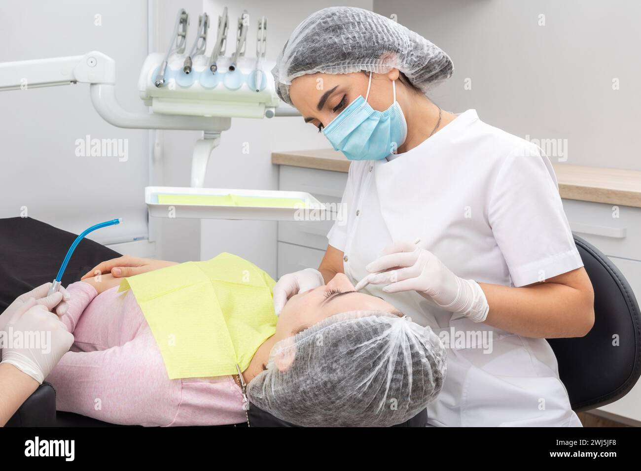 Chirurgo dentista professionista e assistente che esegue un intervento dentistico in una clinica con attrezzature moderne Foto Stock