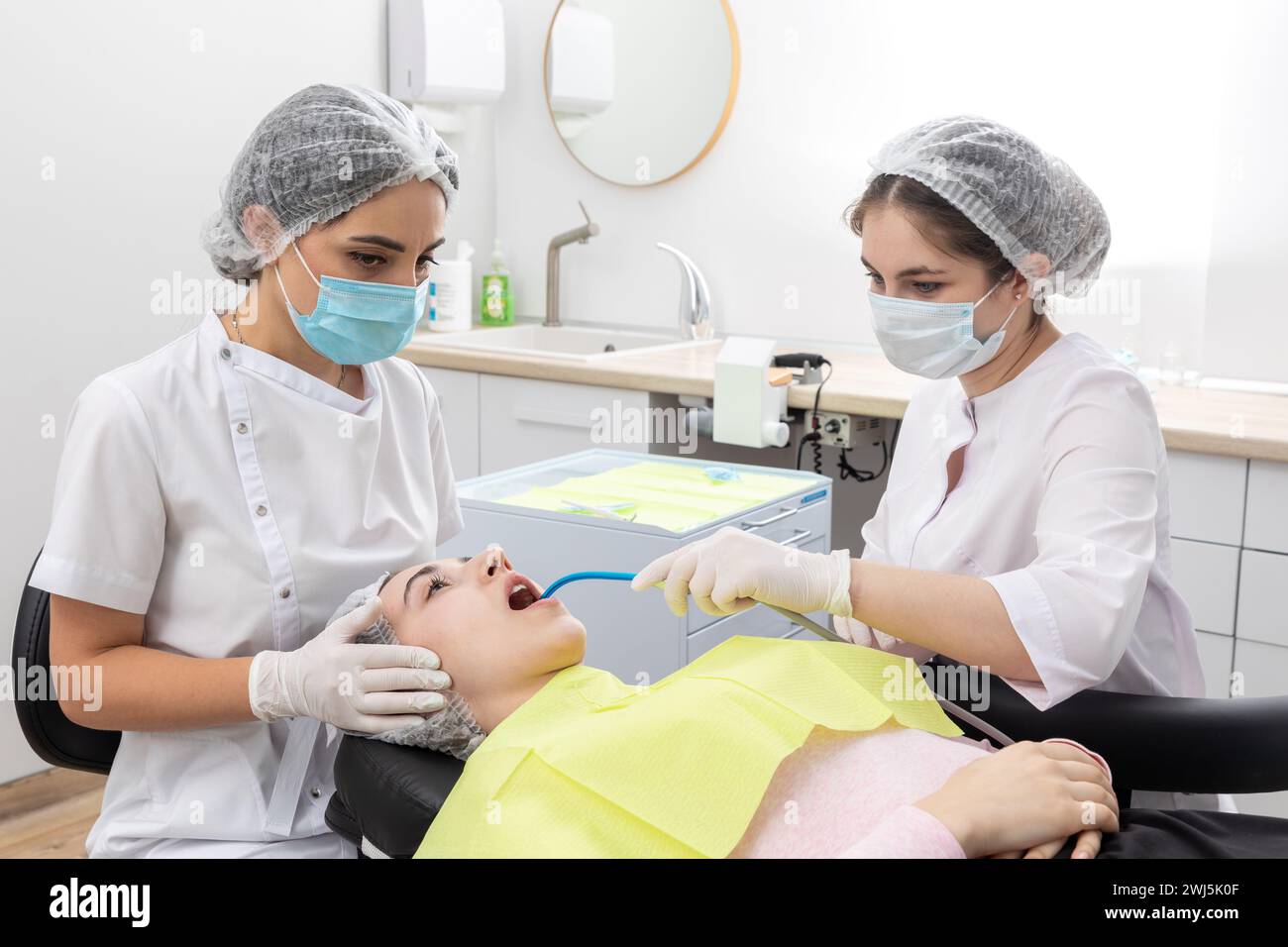 Chirurgo dentista professionista e assistente che esegue un intervento dentistico in una clinica con attrezzature moderne Foto Stock