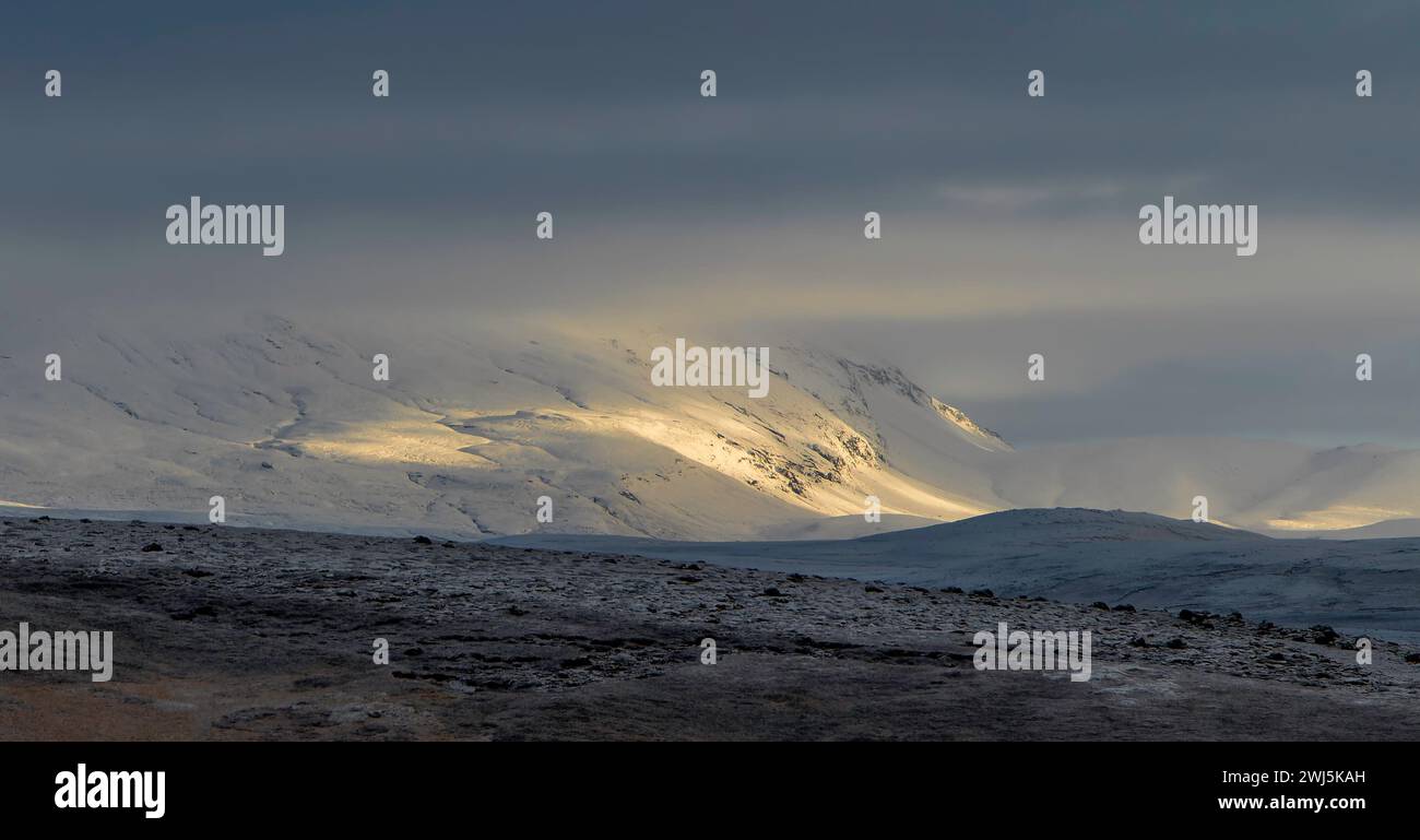 Pittoresco paesaggio nebbioso e catena montuosa ricoperta di ghiaccio durante il freddo inverno contro il cielo grigio in un'area remota durante le nevicate Foto Stock