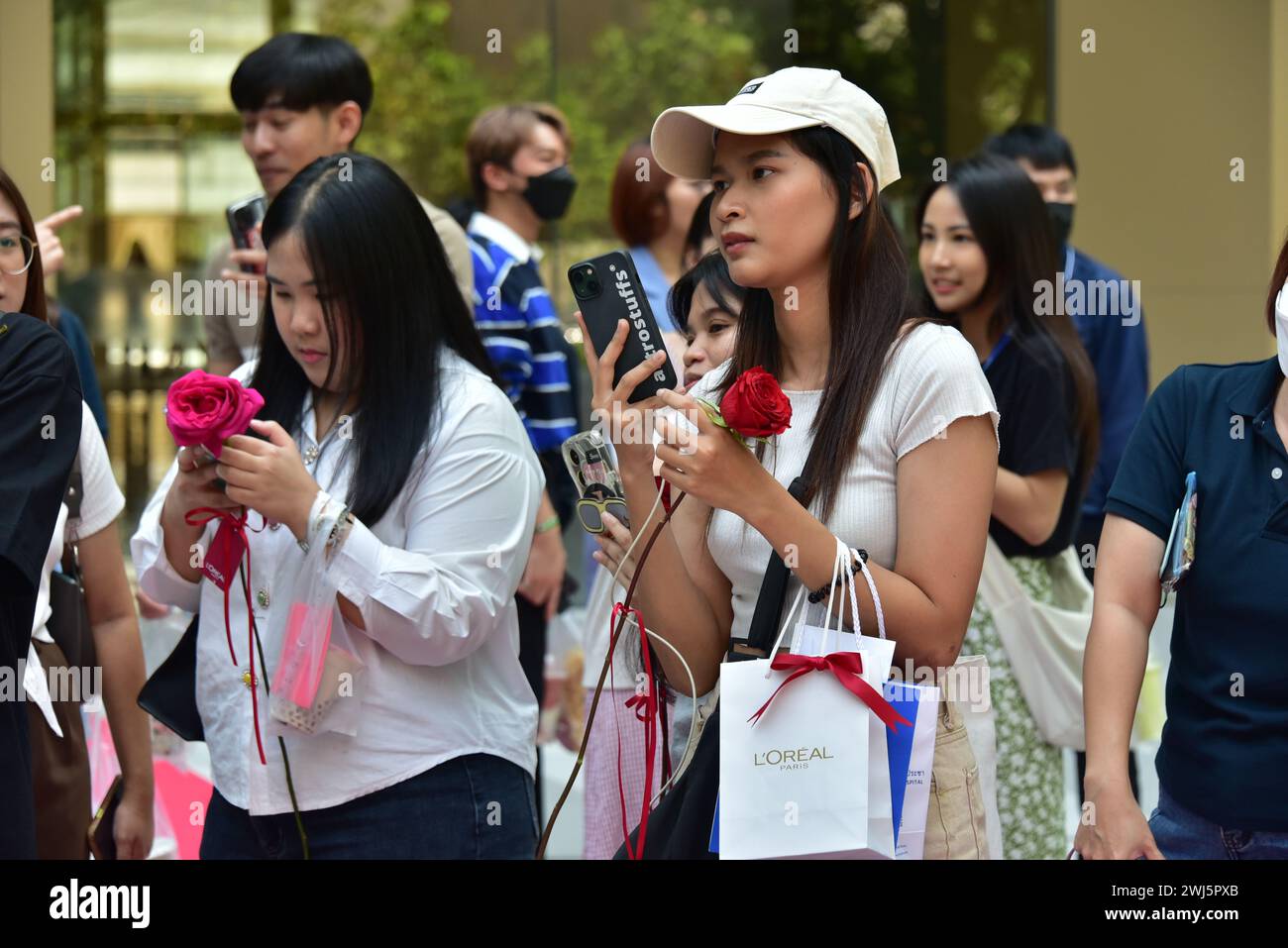 La promozione del marchio l'Oréal per san valentino 2024 nel centro di Bangkok, Thailandia, Sud Est Asiatico, include giovani donne alle quali è stata data una rosa da un famoso cantante Foto Stock