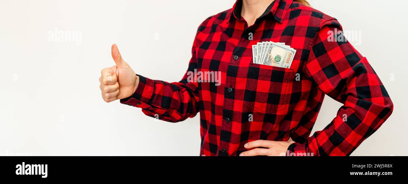 Trasferimenti di denaro. Donna con banconote da dollari in tasca della sua camicia rossa che gestiva il pollice verso l'alto. Foto Stock