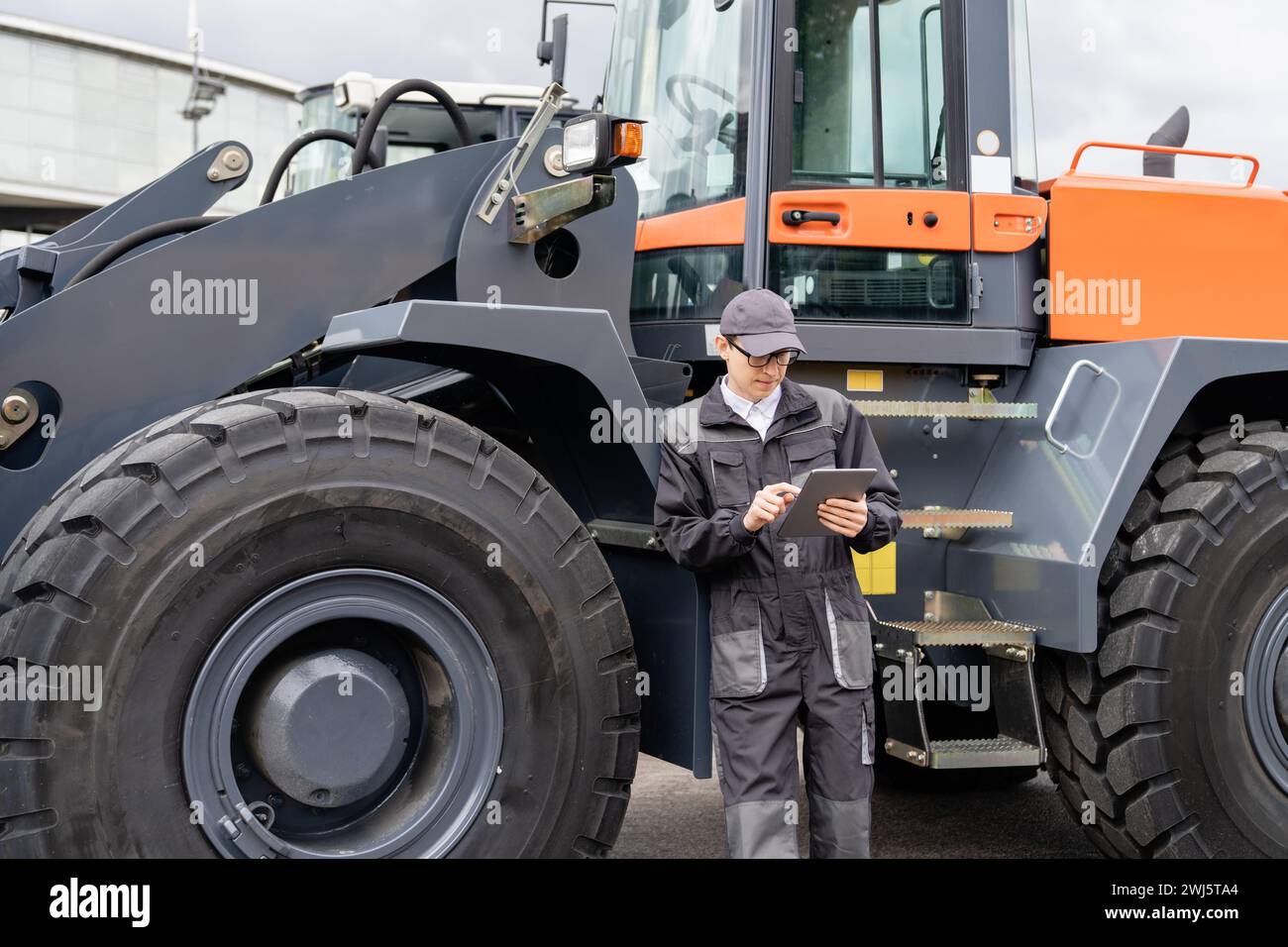 Addetto alla manutenzione con tablet digitale sullo sfondo del trattore. Foto Stock