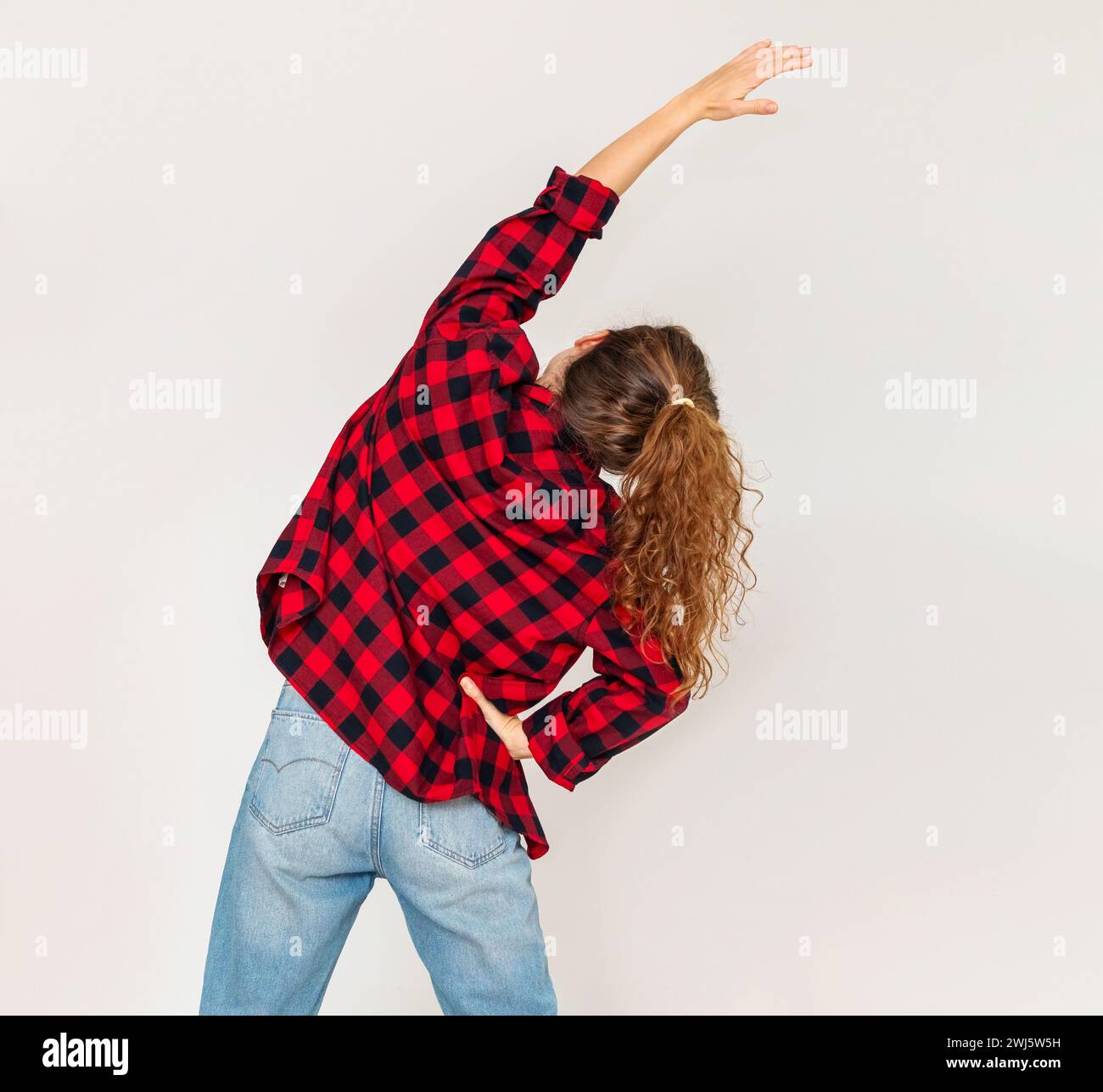 Vista posteriore casual che indossa una giovane donna che fa esercizi di stretching del corpo. Foto Stock