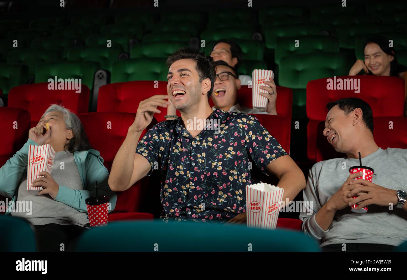 Gruppo di amici asiatici anziani che guardano film comici e ridono al cinema con popcorn Foto Stock