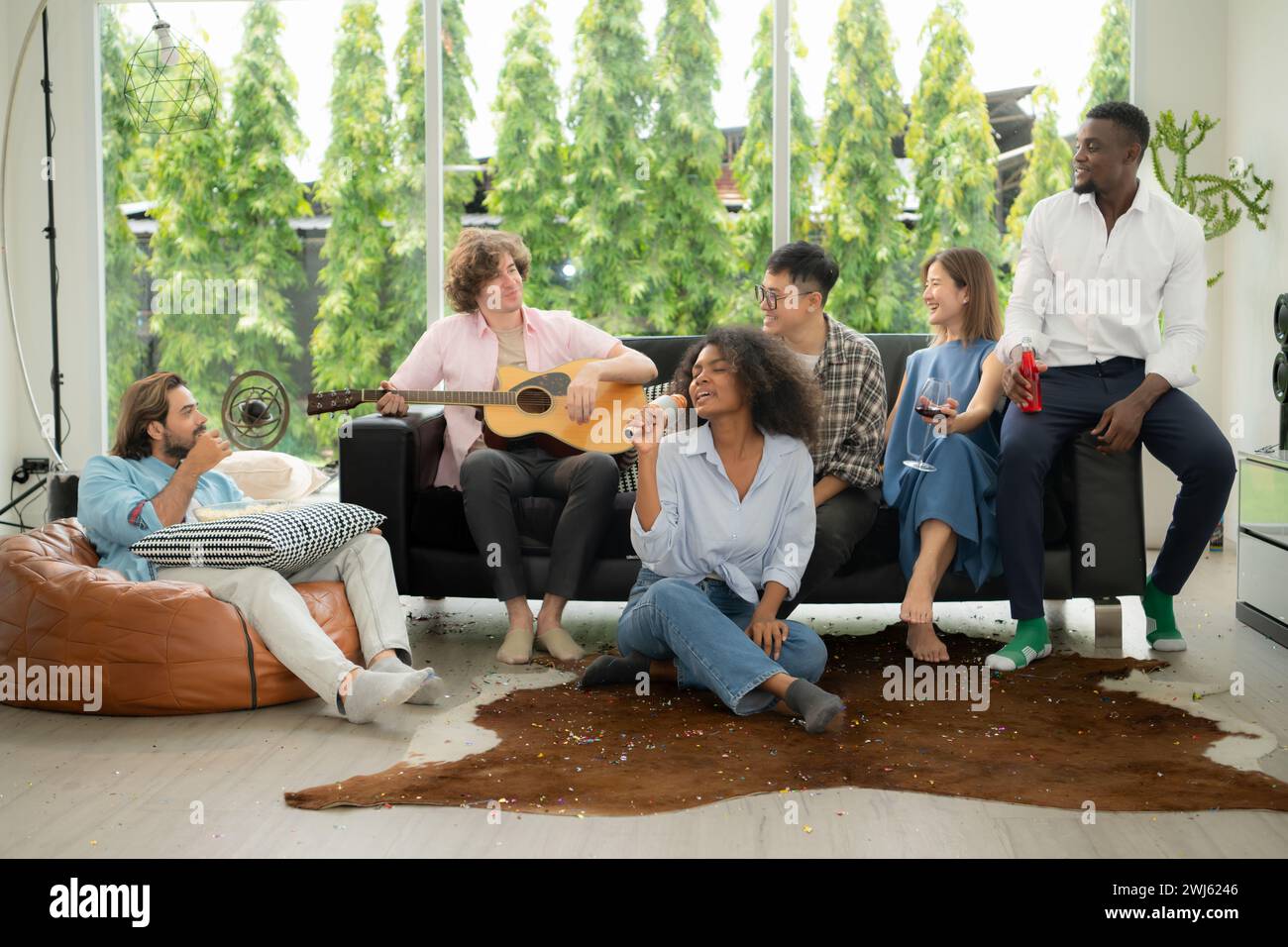 Gruppo di amici multietnici che si divertono alla festa suonando la chitarra e cantando insieme a casa. Foto Stock