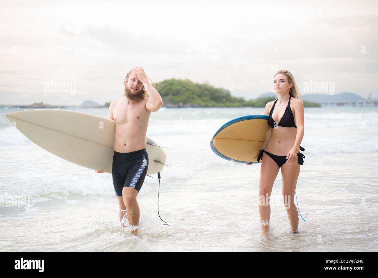 Giovane uomo e donna con tavole da surf pronti a camminare in mare per fare surf. Foto Stock