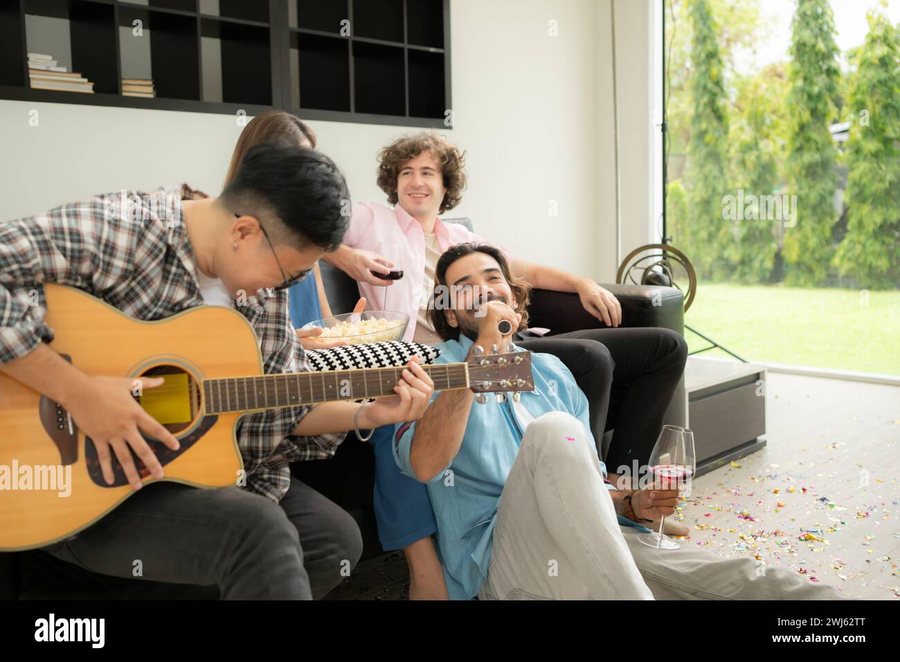 Gruppo multietnico di amici che si divertono a suonare la chitarra e a cantare insieme a casa Foto Stock