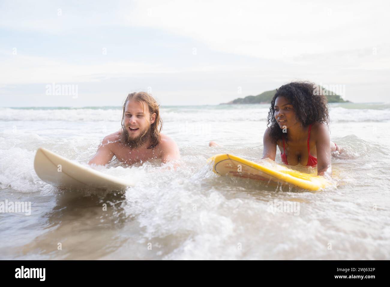 Giovane uomo e donna che si divertono con la tavola da surf nell'oceano in una giornata di sole Foto Stock