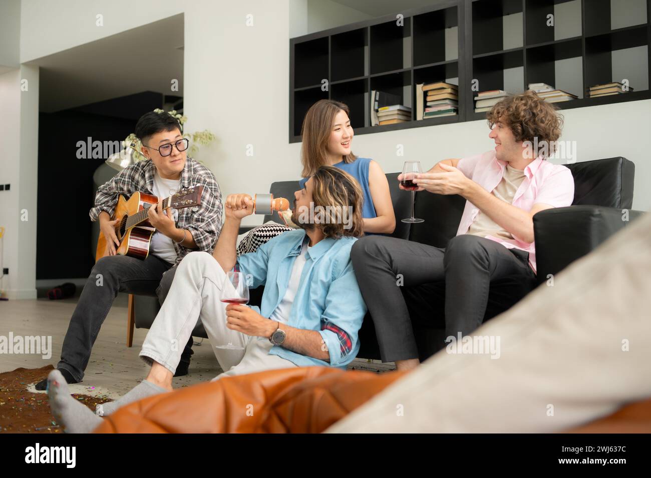 Gruppo multietnico di amici che si divertono a suonare la chitarra e a cantare insieme a casa Foto Stock
