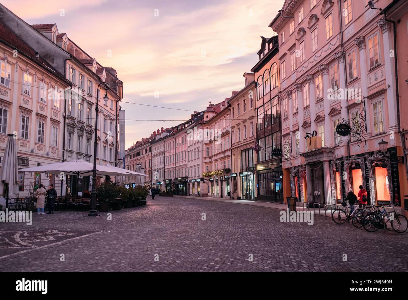 Un'affascinante scena notturna caratterizzata da un'architettura vintage e da vivaci pedoni in una strada trafficata Foto Stock
