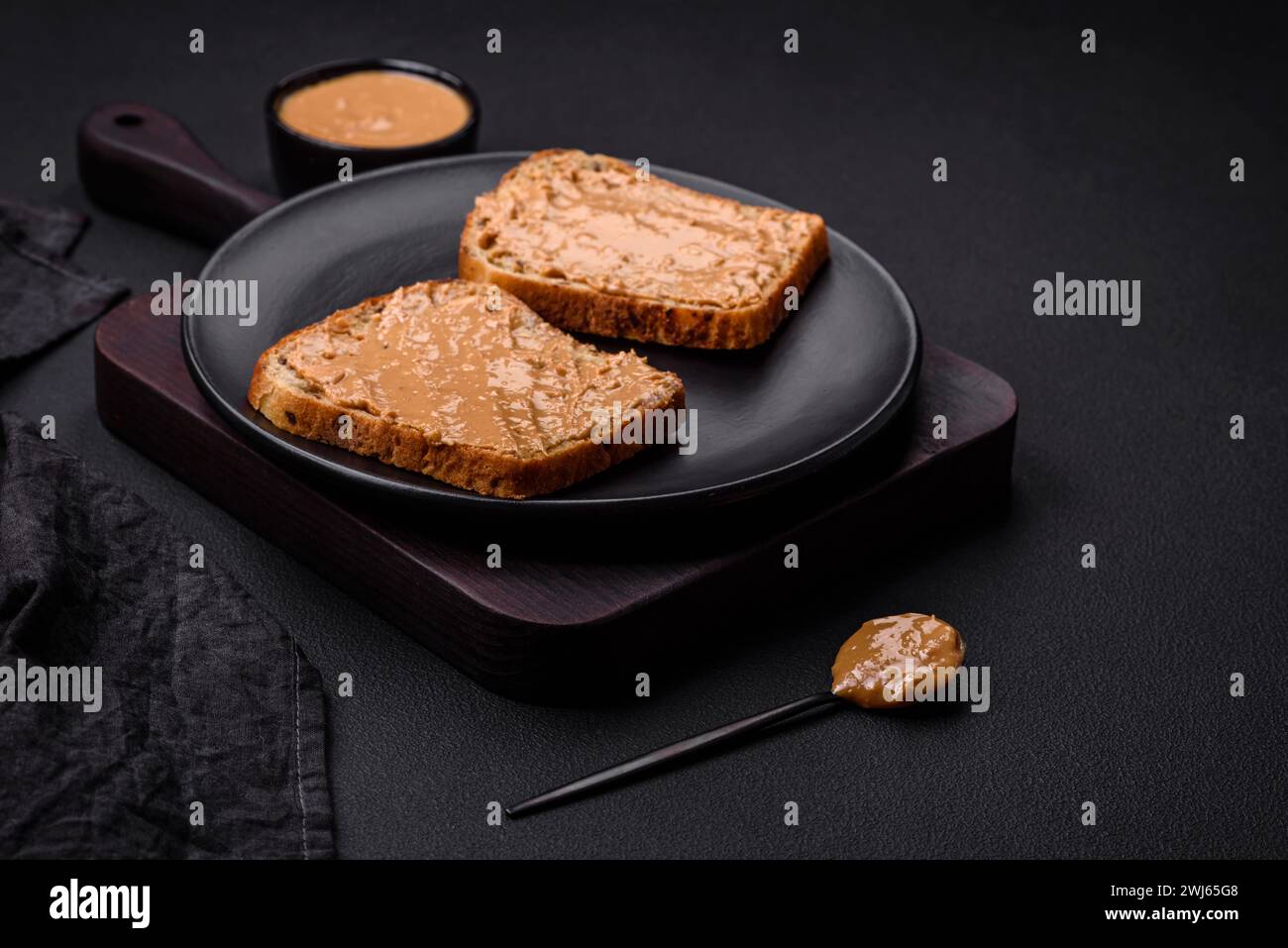 Sandwich nutriente composto da pane e burro di arachidi su un piatto di ceramica nera Foto Stock
