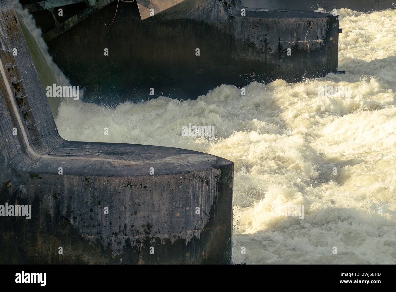 Acqua che spara attraverso la diga di una centrale elettrica, schiumogendosi e creando spruzzi. Foto Stock