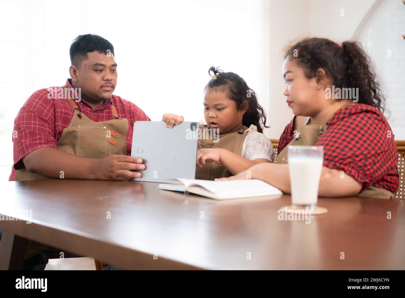 Una famiglia di grandi dimensioni con un padre che indossa una protesi alla gamba, assiste felicemente un bambino con i compiti e si diverte insieme Foto Stock