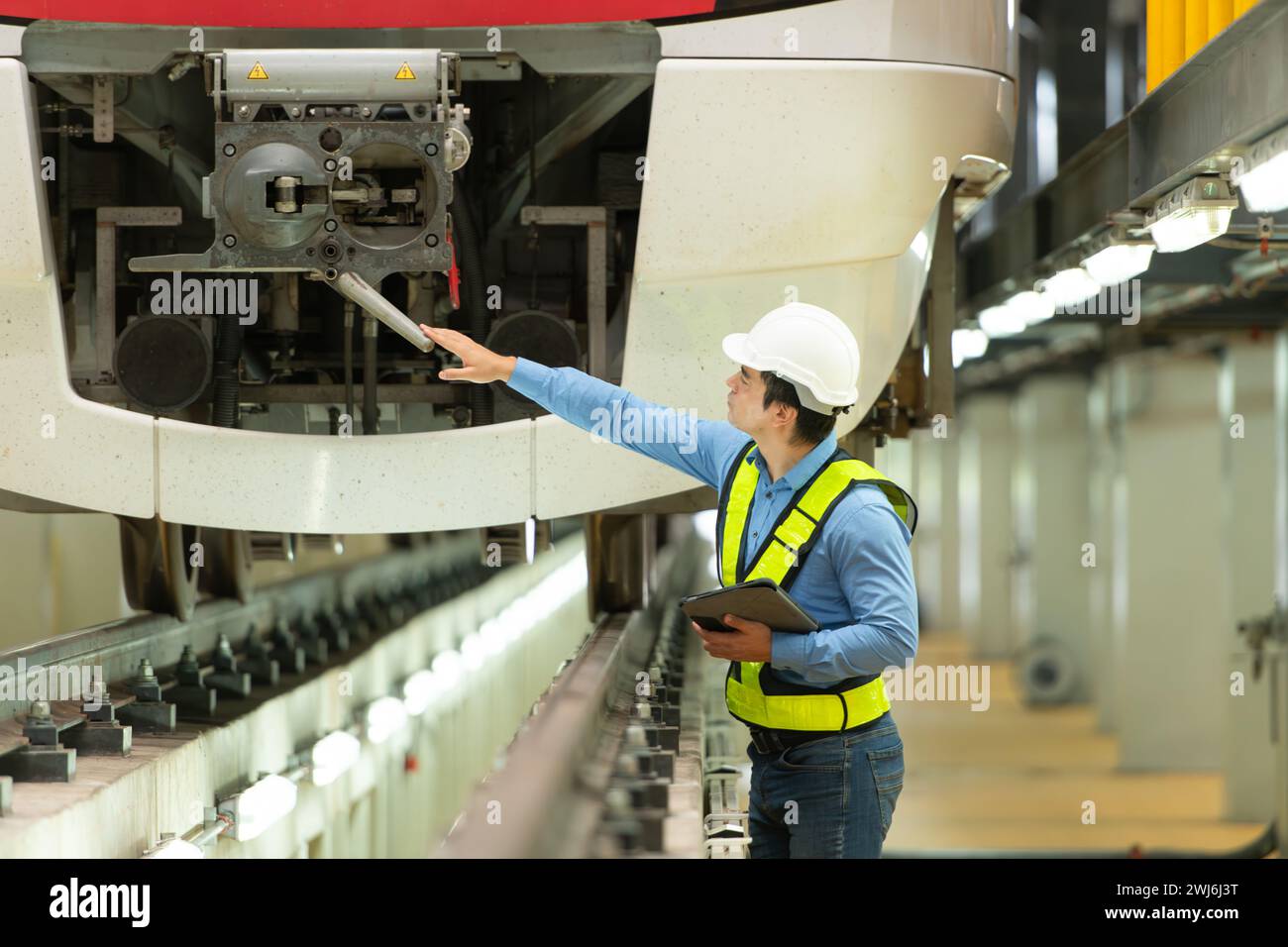 Dopo che il treno elettrico è parcheggiato nell'officina di riparazione del treno elettrico, l'ingegnere del treno elettrico ispeziona il treno elettrico Foto Stock