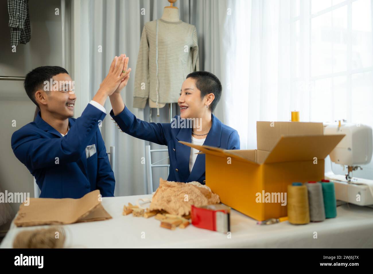 Entrambi gli stilisti asiatici che lavorano con la macchina da cucire nel negozio di abiti da sposa Foto Stock