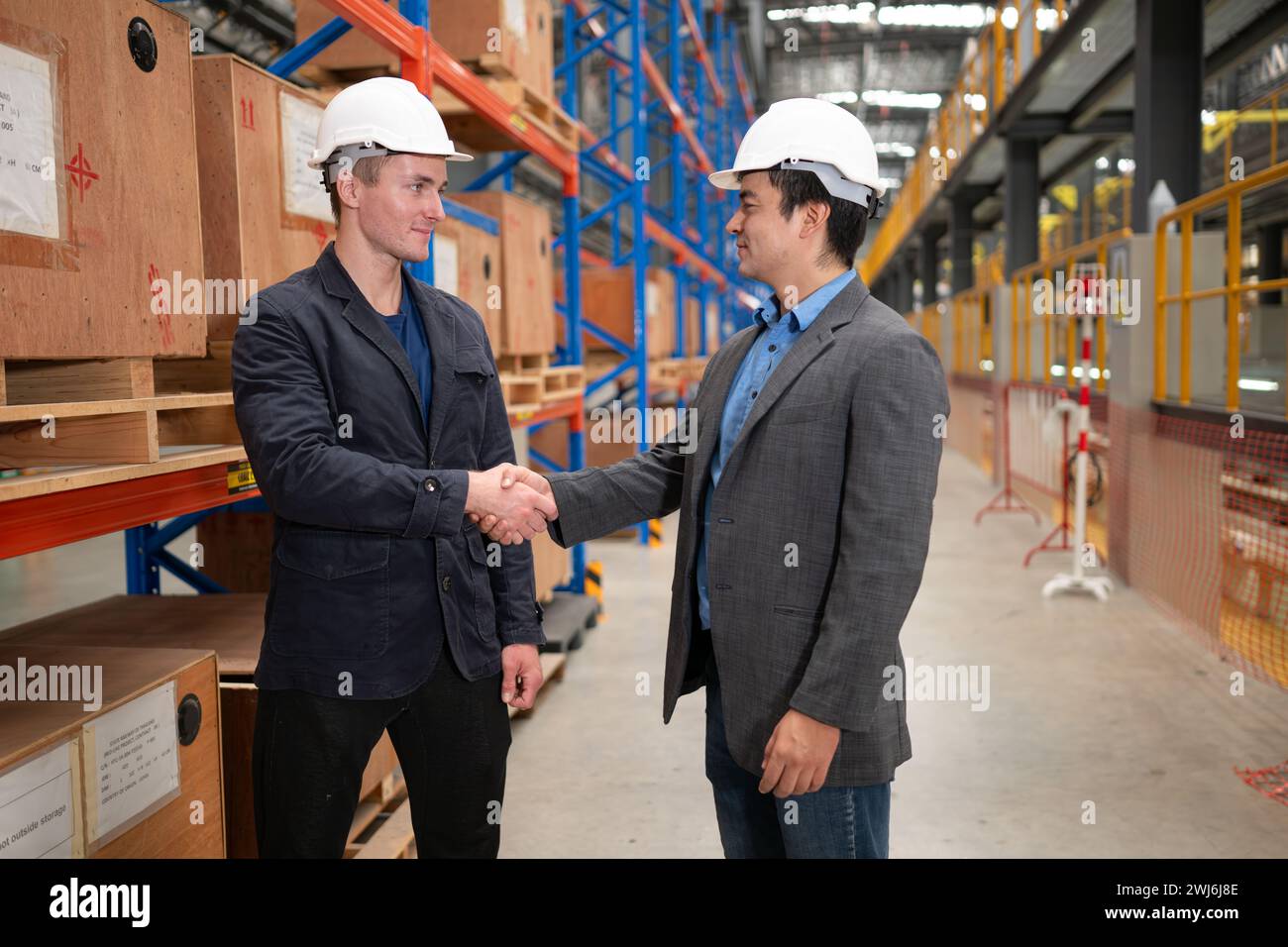 Due uomini d'affari che stringono la mano in un magazzino si tratta di un magazzino di pezzi di ricambio e attrezzature per la riparazione di macchinari e passenge Foto Stock