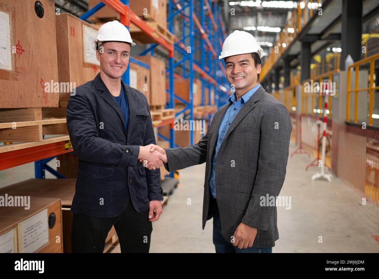 Due uomini d'affari che stringono la mano in un magazzino si tratta di un magazzino di pezzi di ricambio e attrezzature per la riparazione di macchinari e passenge Foto Stock