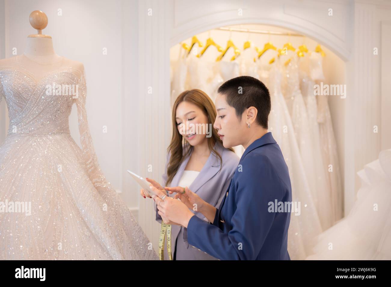 Entrambi gli stilisti asiatici che lavorano con abiti da sposa nel negozio di abiti da sposa Foto Stock
