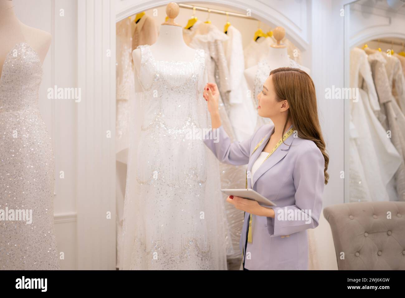 Il proprietario del negozio è un designer e un sarto. Stiamo esaminando abiti da sposa pronti per la sposa e lo sposo tra cui scegliere Foto Stock