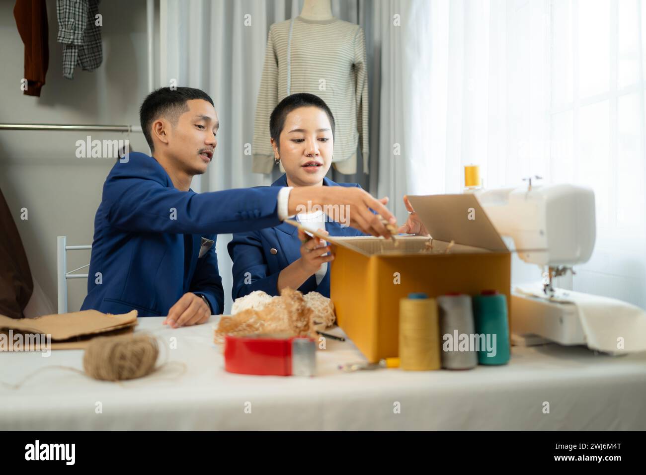 Giovani uomini d'affari asiatici e abiti da donna vengono confezionati per la consegna ai clienti in scatole di cartone e in grumi imbottiti Foto Stock