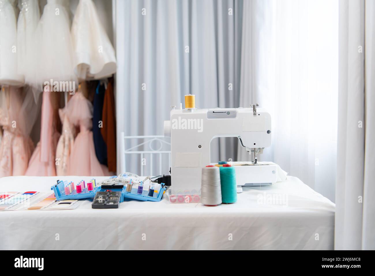 Macchina da cucire e accessori sul tavolo per il lavoro di un sarto di abiti da sposa Foto Stock