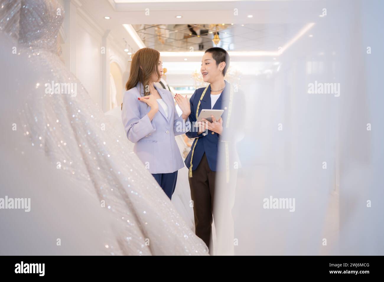 Entrambi gli stilisti asiatici che lavorano con abiti da sposa nel negozio di abiti da sposa Foto Stock