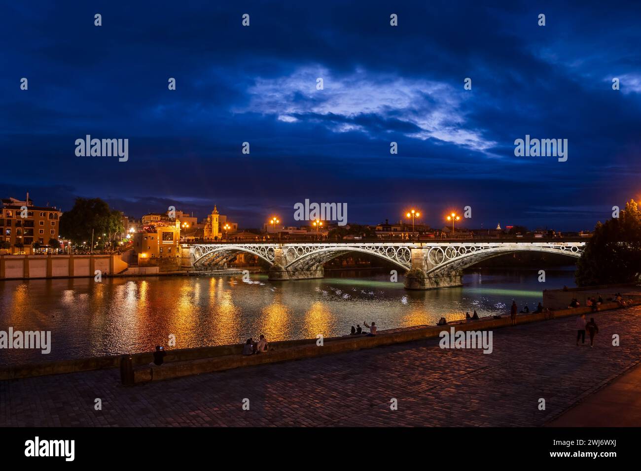 Ponte Triana (Puente de Isabel II) sul fiume Guadalquivir di notte nella città di Siviglia, Andalusia, Spagna. Foto Stock