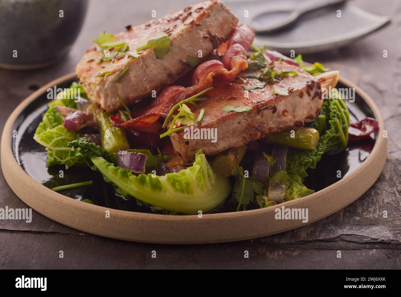 Bistecche di tonno scottate con pancetta su un letto di verdure. Foto Stock
