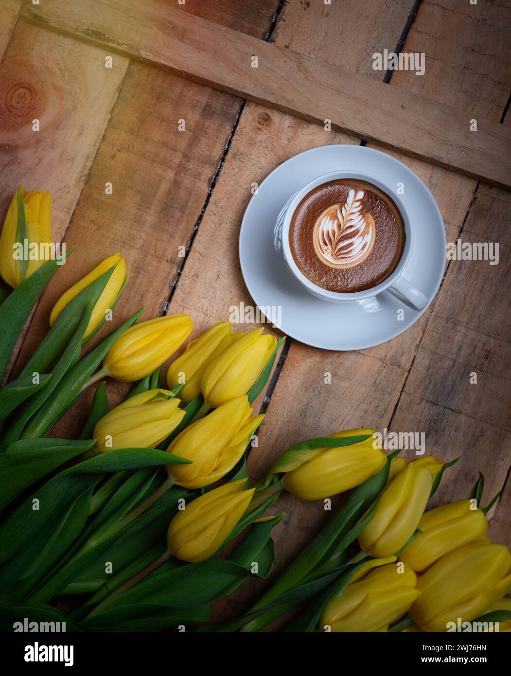 Tazza da caffè con fiori di tulipani gialli e note buongiorno su un tavolo rustico blu dall'alto, colazione nella giornata delle madri o delle donne Foto Stock