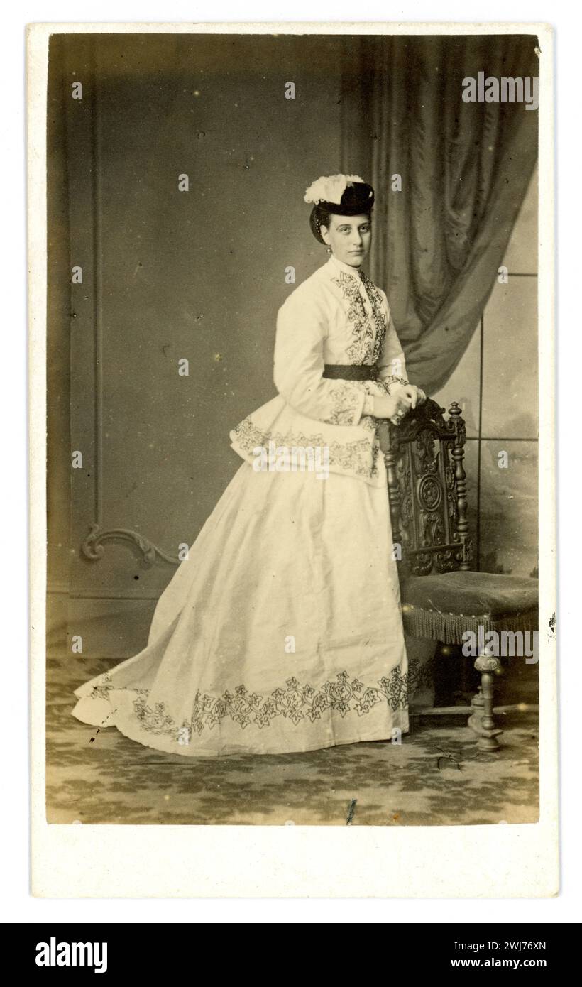 Originale CDV Vittoriano degli anni '1860 carte de visite (biglietto da visita o CDV) di bella elegante donna vittoriana che indossa un bellissimo vestito con un treno in due pezzi - una gonna e un paletot (o giacca). I suoi capelli sono vestiti con un panino di chignon e un piccolo cappello con piume. Dallo studio di William Bartholomew, Egham, Surrey, Regno Unito circa 1867 / 1868 / 1869. Foto Stock