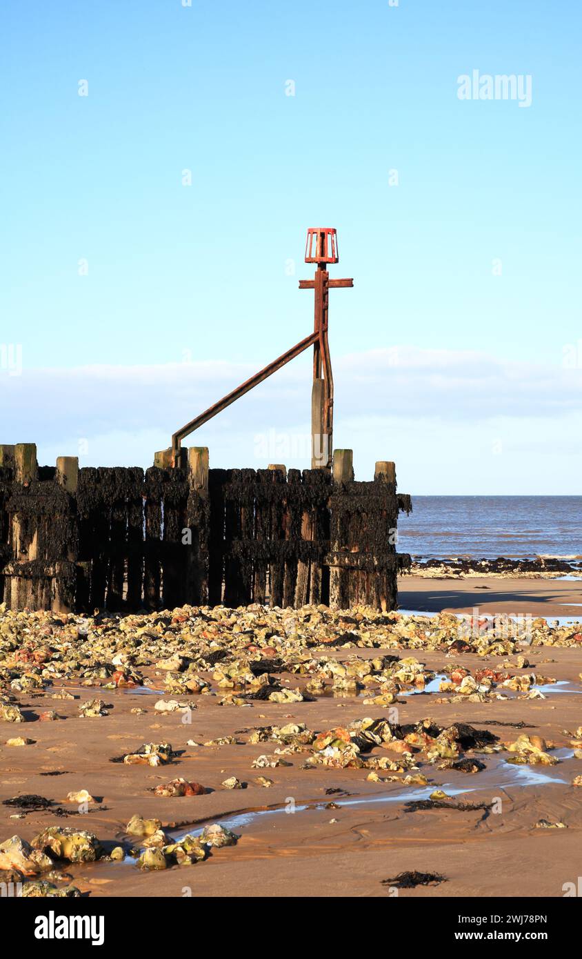 Un palo segnaletico alla fine di un'estesa frangiflutti in legno rivelata durante la bassa marea sulla costa del Norfolk settentrionale a West Runton, Norfolk, Inghilterra, Regno Unito. Foto Stock
