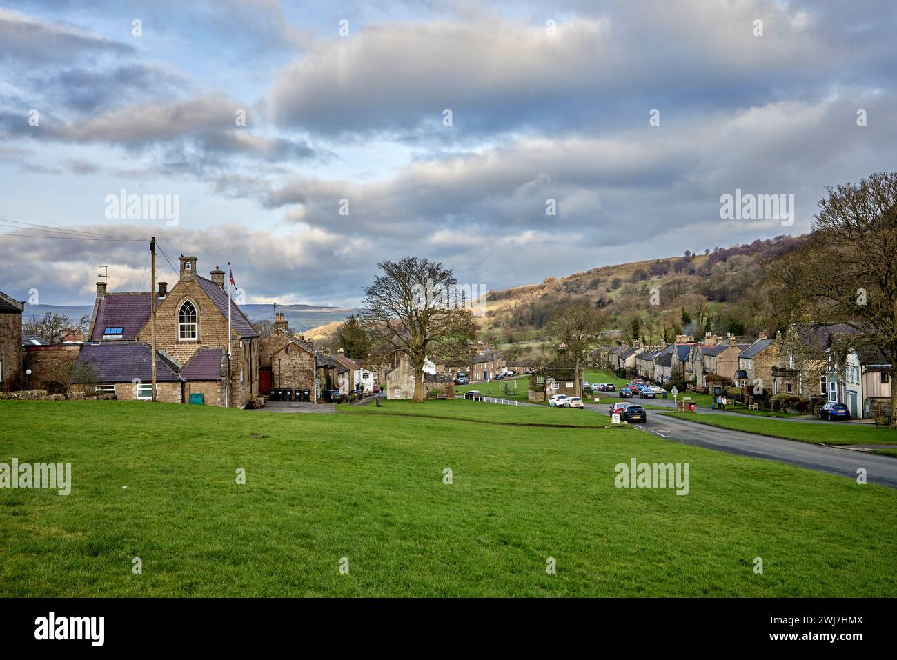 Centro di West Burton con case domestiche, il pub Fox & Hounds, l'ottagonale Market Cross, l'ampio villaggio verde e le auto parcheggiate. Foto Stock