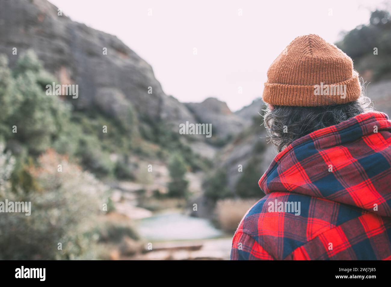 Uomo con un cappotto rosso a quadri che guarda il fiume Foto Stock