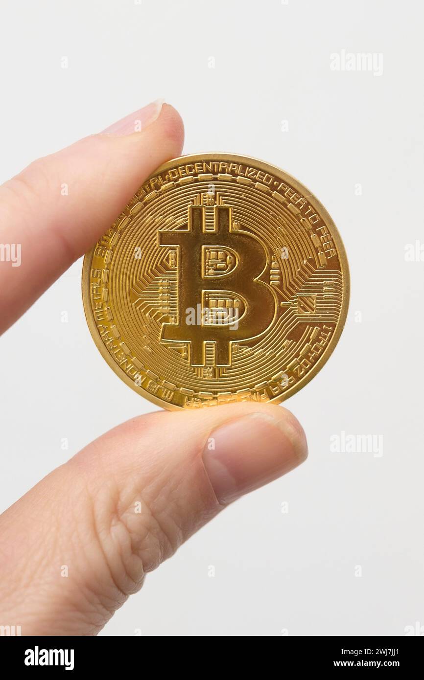 Moneta Bitcoin tra le dita Foto Stock