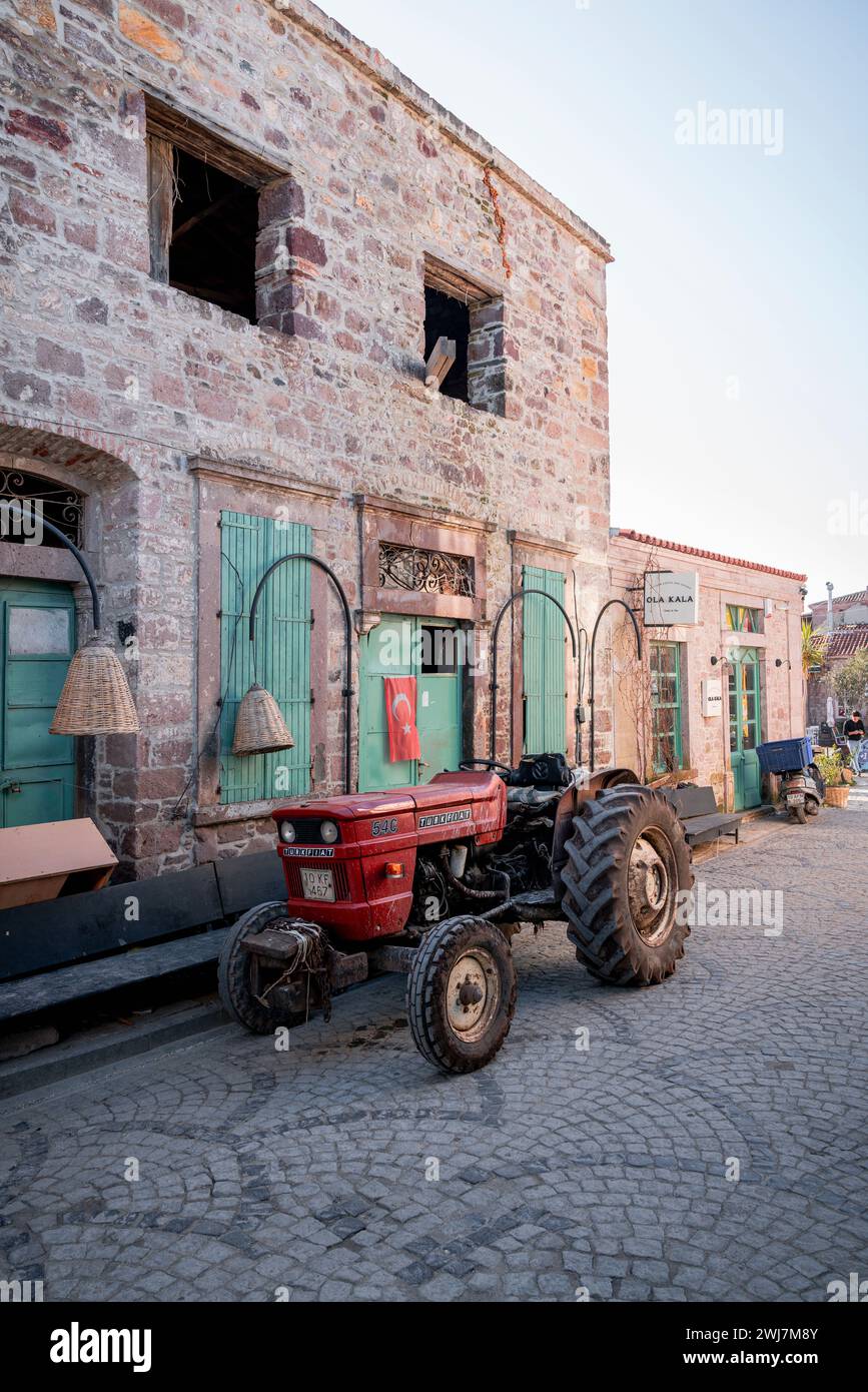 Il lavoro di Dawn: Il tranquillo viaggio del trattore rosso attraverso le strade del risveglio di Ayvalık Foto Stock