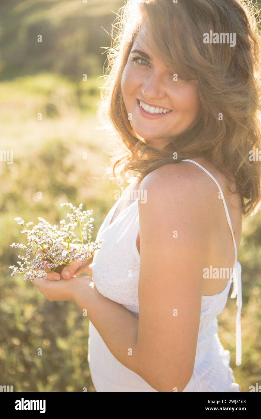 Donna sorridente con capelli volanti al tramonto estivo Foto Stock