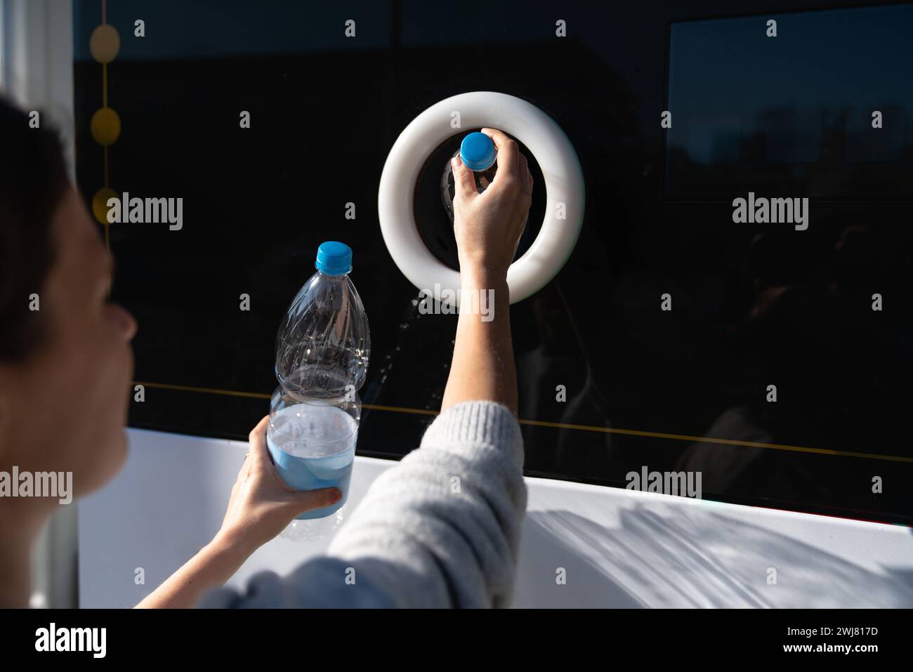 La donna usa una macchina self-service per ricevere bottiglie e lattine di plastica usate in una strada cittadina. Foto Stock