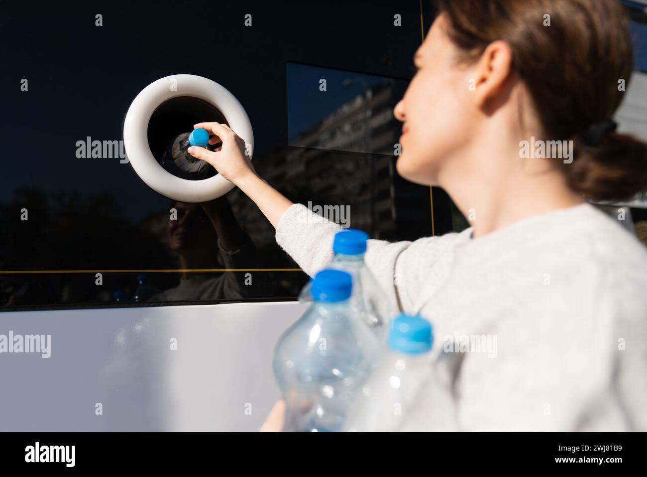 La donna usa una macchina self-service per ricevere bottiglie e lattine di plastica usate in una strada cittadina. Foto Stock