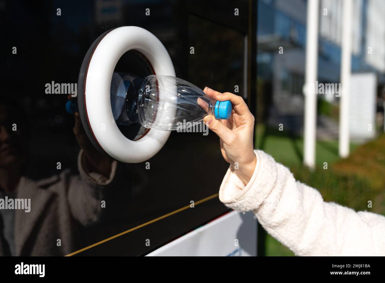 La donna usa una macchina self-service per ricevere bottiglie e lattine di plastica usate in una strada cittadina. Foto Stock
