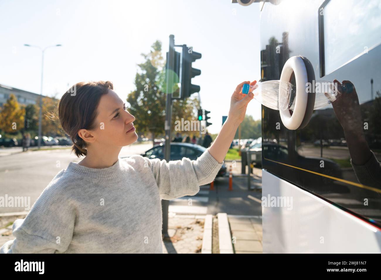 La donna usa una macchina self-service per ricevere bottiglie e lattine di plastica usate in una strada cittadina. Foto Stock