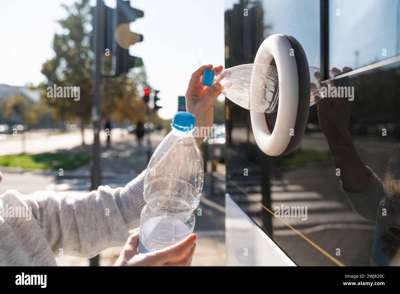 La donna usa una macchina self-service per ricevere bottiglie e lattine di plastica usate in una strada cittadina. Foto Stock