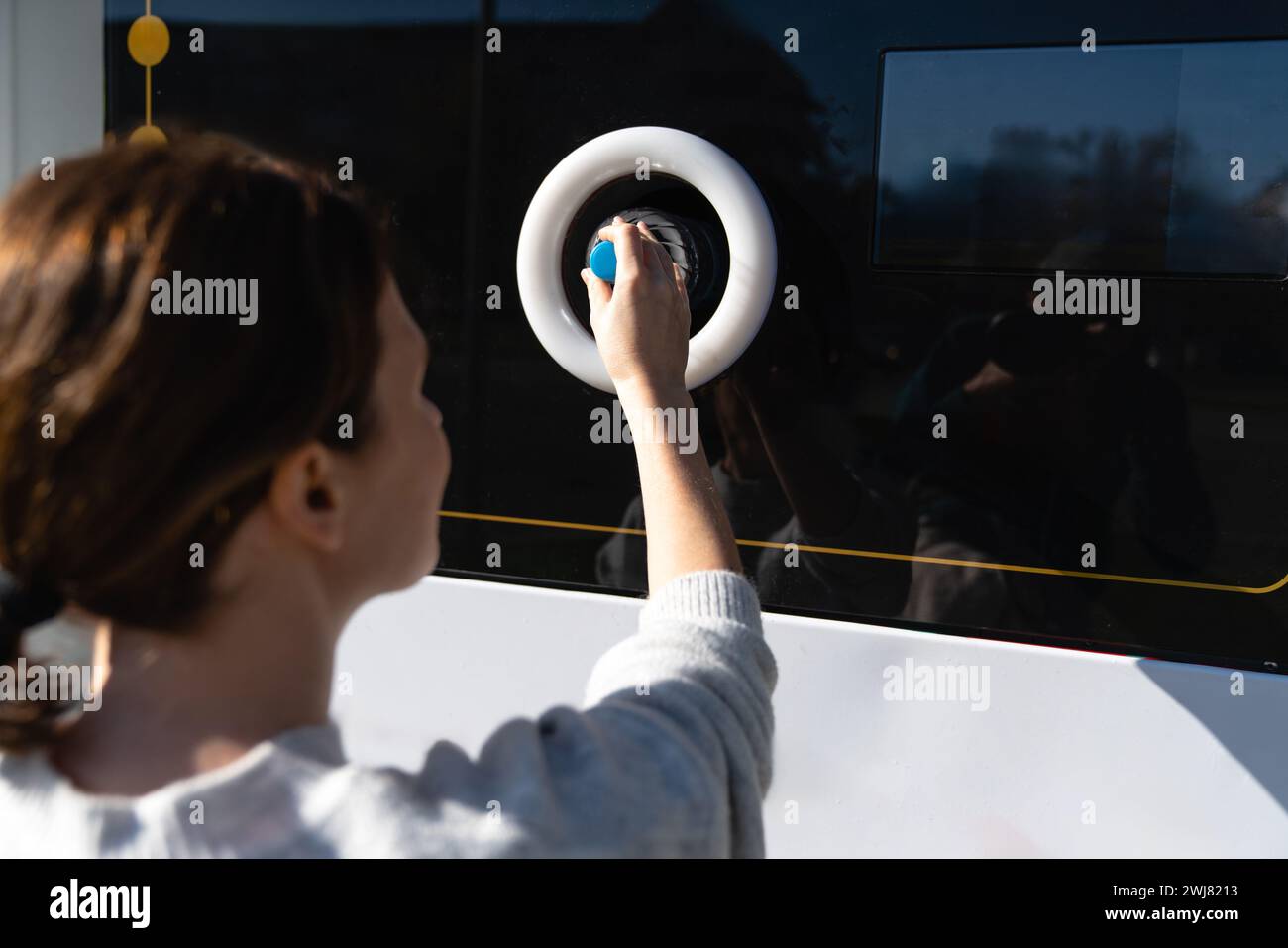 La donna usa una macchina self-service per ricevere bottiglie e lattine di plastica usate in una strada cittadina. Foto Stock