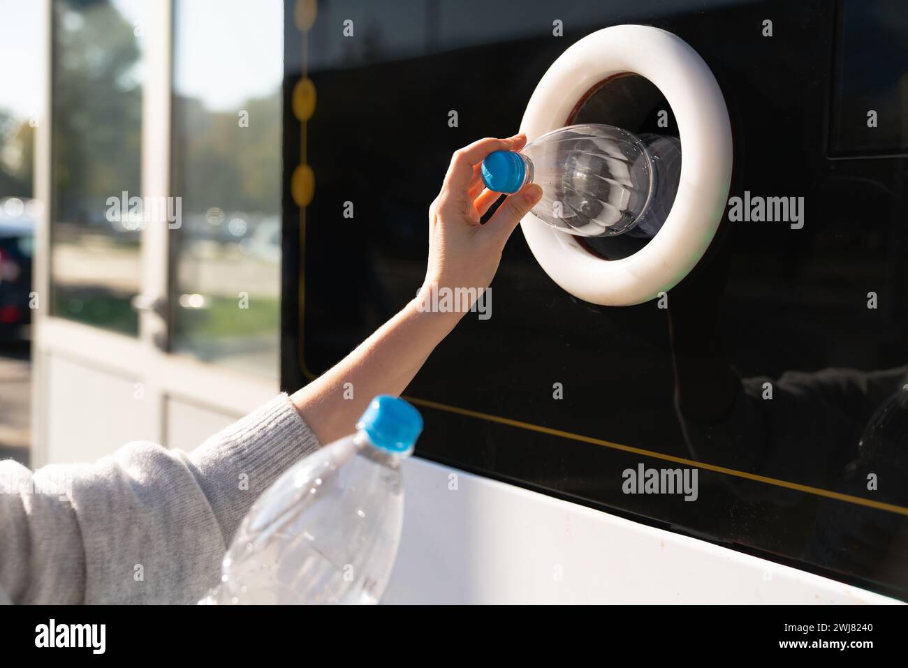 La donna usa una macchina self-service per ricevere bottiglie e lattine di plastica usate in una strada cittadina. Foto Stock