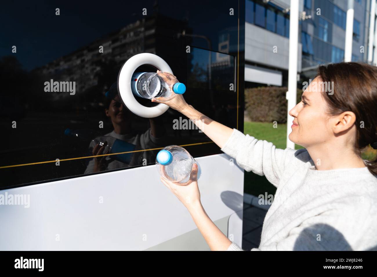 La donna usa una macchina self-service per ricevere bottiglie e lattine di plastica usate in una strada cittadina. Foto Stock