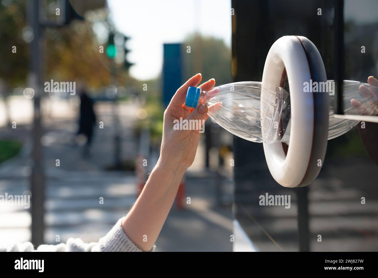 La donna usa una macchina self-service per ricevere bottiglie e lattine di plastica usate in una strada cittadina. Foto Stock