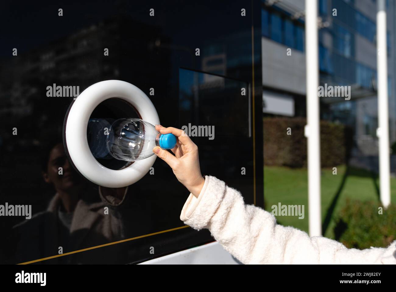 La donna usa una macchina self-service per ricevere bottiglie e lattine di plastica usate in una strada cittadina. Foto Stock