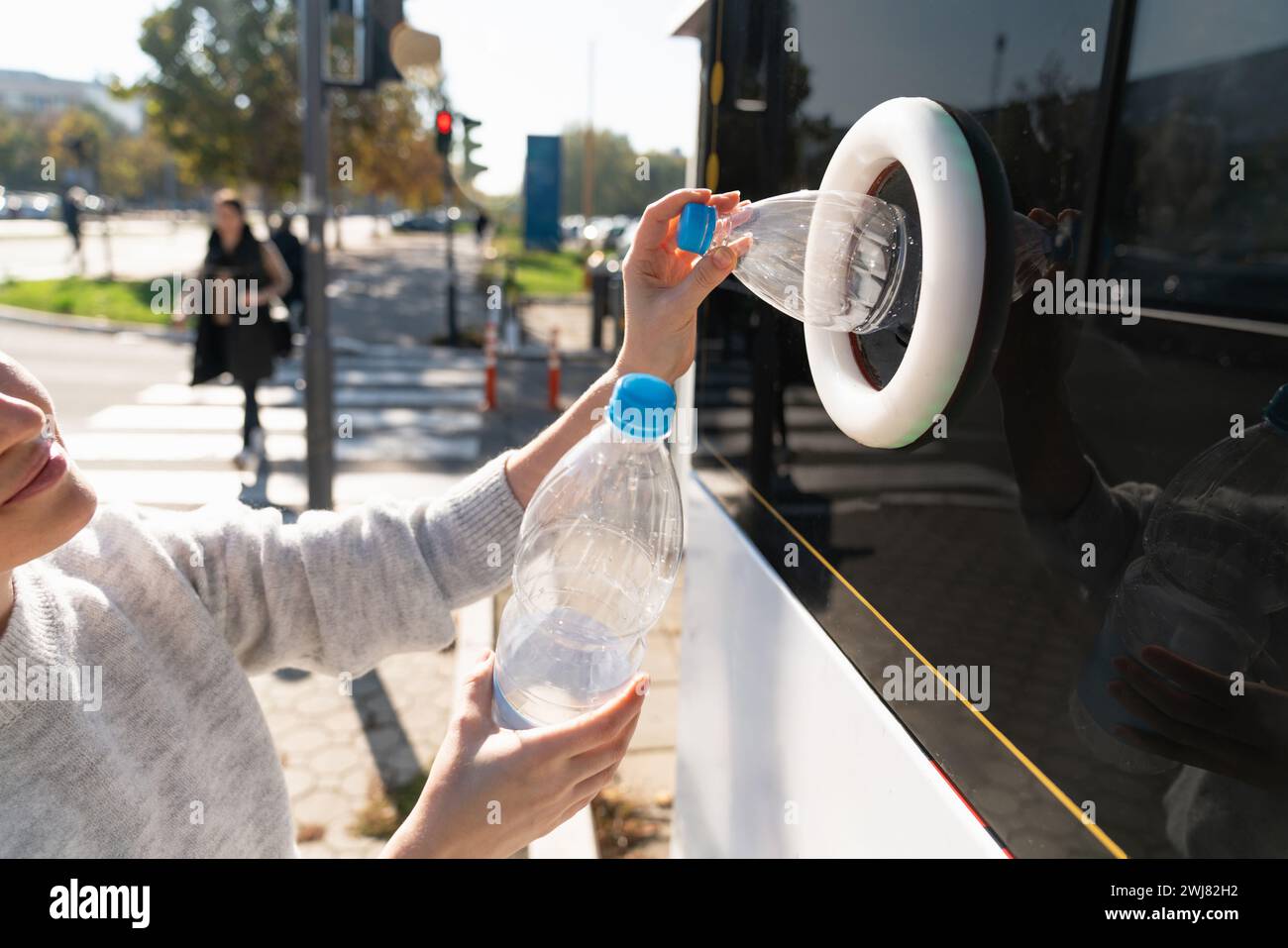 La donna usa una macchina self-service per ricevere bottiglie e lattine di plastica usate in una strada cittadina. Foto Stock