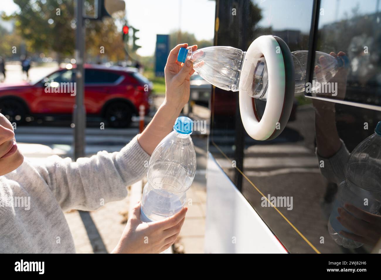 La donna usa una macchina self-service per ricevere bottiglie e lattine di plastica usate in una strada cittadina. Foto Stock