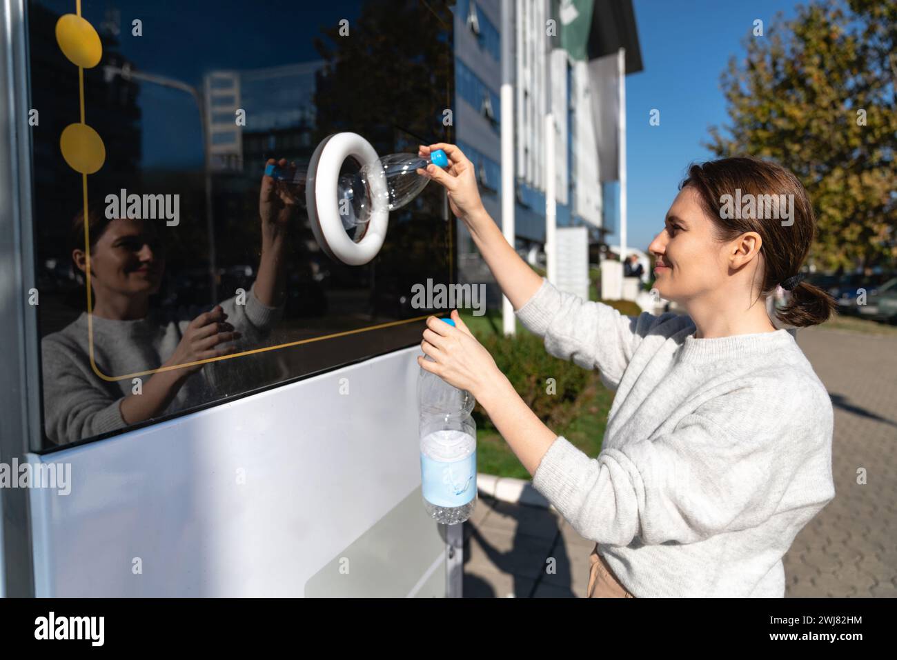 La donna usa una macchina self-service per ricevere bottiglie e lattine di plastica usate in una strada cittadina. Foto Stock